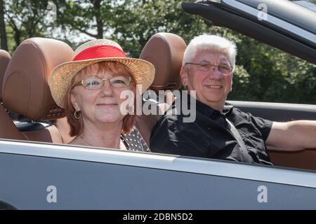 Older couple drives with a luxury convertible car Stock Photo