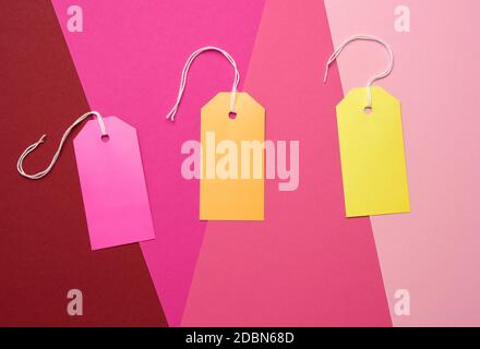 paper rectangular tags on a rope on a colored background, flat lay. Price tag, gift, for writing address Stock Photo