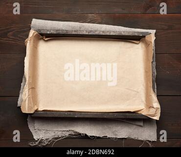 empty rectangular metal pan covered with brown parchment paper on a wooden table, top view Stock Photo