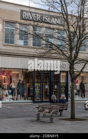 a large high street branch of the river island clothing story in southampton city centre with two women sitting on a bench outside. Stock Photo