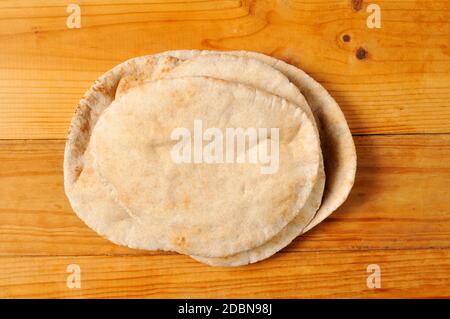 Whole wheat pita bread on a rustic wooden table Stock Photo