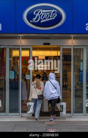 two women entering a large high street boots the chemist store in southampton city centre Stock Photo