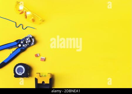 Different electrician's supplies on yellow background. Background of professional electrician tools with space for text Stock Photo