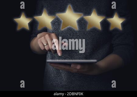 Five stars service rating concept. Woman with a digital tablet in hands with a 5 golden stars above a screen Stock Photo