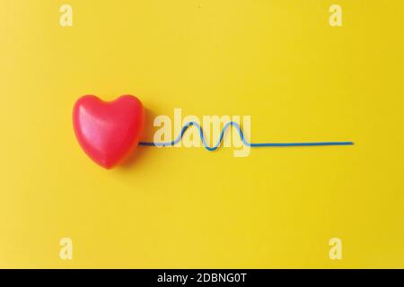 Red heart with a blue curved wire depicting a heartbeat. Healthy Concept. Vital energy concept Stock Photo