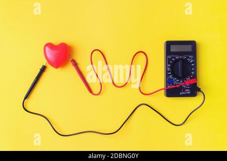 Digital multimeter with probes and backlit display on a yellow background. A multimeter or a multitester is an electronic measuring instrument Stock Photo