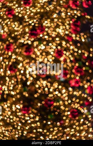 Lots of bright yellow-orange defocused Christmas lights from the garland. Group of golden colorful blurry lights for the new year on the tree Stock Photo