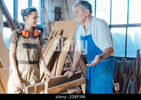 Senior carpenter sharing wisdom with younger aspiring woman colleague Stock Photo