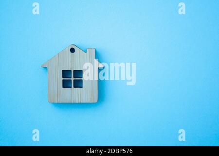 House, insurance and mortgage, buing and rent concept. Small wooden house toy on blue background top view with copy space Stock Photo