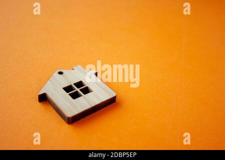 House, insurance and mortgage, buing and rent concept. Small wooden house toy on orange background side view copyspace Stock Photo