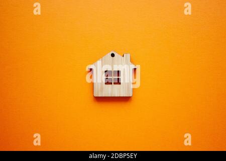 House, insurance and mortgage, buing and rent concept. Small wooden house toy on orange background top view Stock Photo