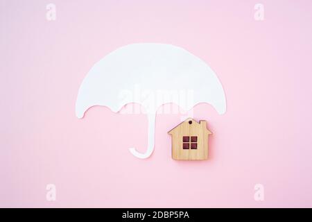 House insurance concept, house protection. Umbrella and wooden toy house for protect your house and property concept. Stock Photo