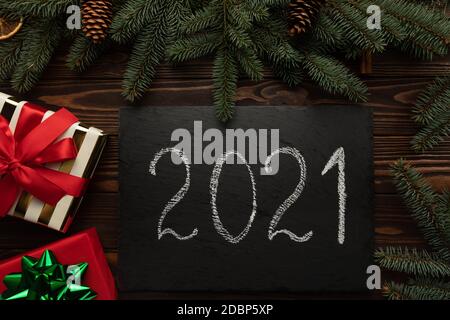 There is a black granite plaque with the words 2021 on the table decorated with Christmas decor. Stock Photo