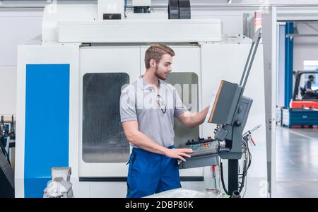 Worker operating computer-controlled machine tool on the screen Stock Photo