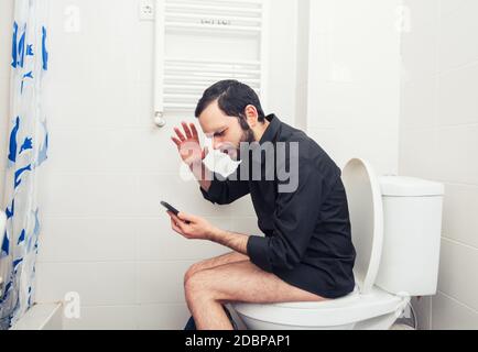 man sitting in toilet and talking on phone Stock Photo