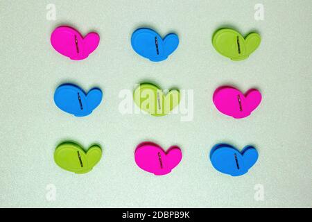 Colourful set of nine plastic clothespins or pegs on a light green sparkling background with copy field. View from above. Stock Photo