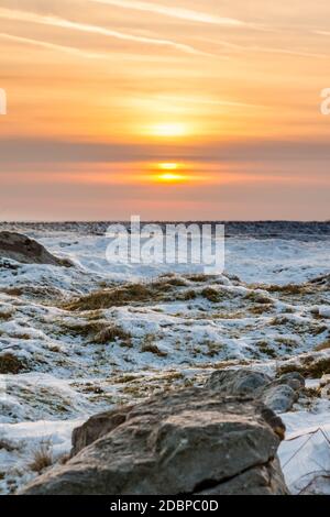 Sunset over a cold, frozen winter landscape on high moorland Stock Photo