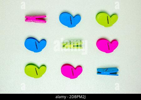 Colourful set of nine plastic clothespins or pegs on a light green sparkling background with copy field. View from above. Stock Photo
