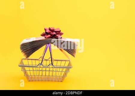 On the handles of the grocery cart lies a bundle of notes packed with gift ribbon and a red bow Stock Photo