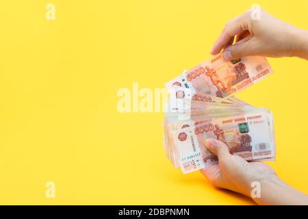 Hands put another bill in a pack of five thousandth bills Stock Photo