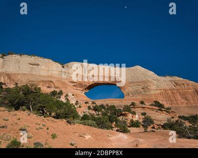 A big hole in the middle of the mountain and above it the moon in broad daylight Stock Photo