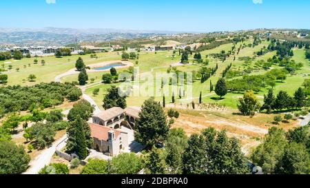 Aerial bird’s eye view of Stavros tis Minthis (St Anthony) monastery and golf course in Tsada village, Paphos, Cyprus from above. Church surrounded by Stock Photo