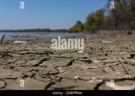 Cracked, muddy ground at the river bank with river Danube in background Stock Photo