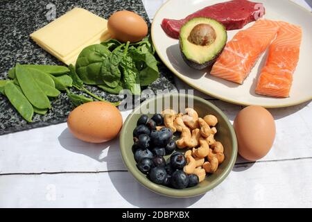 low carb ketogenic gluten free paleo style diet protein based meat fish dairy eggs veg berries and nuts background with copy space Stock Photo
