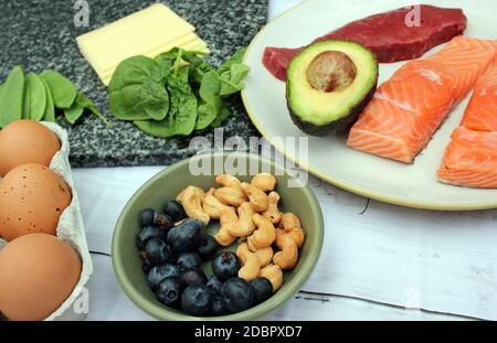 low carb ketogenic gluten free paleo style diet protein based meat fish dairy eggs veg berries and nuts background with copy space Stock Photo