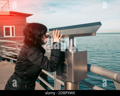 Woman looking in binoculars on the sea deck Stock Photo