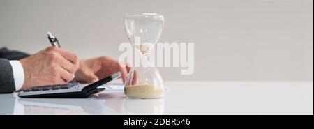 Late Invoice And Hourglass Deadline Working In Office Stock Photo