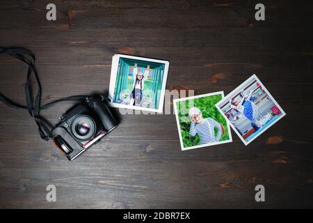 Photos and vintage camera on wood table background. Flat lay. Stock Photo