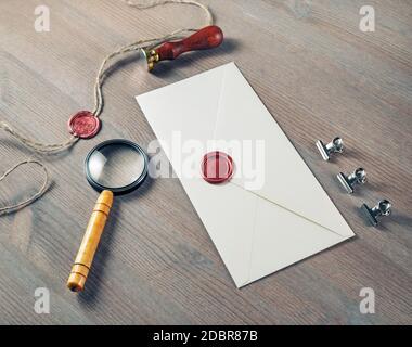 Vintage letter envelope with red wax seal, stamp and magnifier on wood table background. Mock-up for your design. Stock Photo