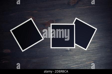 Three blank square photo frames on wood table background. Top view. Flat lay. Stock Photo
