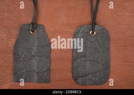 Two blank black leather tag label on brown leather. View from above Stock Photo