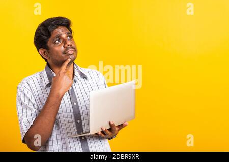 Closeup Asian happy portrait young black man holds a laptop computer hand finger handle on the chin and thinking question looking away, studio isolate Stock Photo