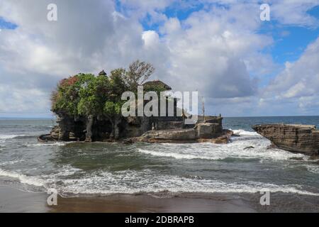 Waves shatter on a cliff at the top of which is the Hindu temple of Tanah Lot. Temple built on a rock in the sea off the coast of Bali island, Indones Stock Photo