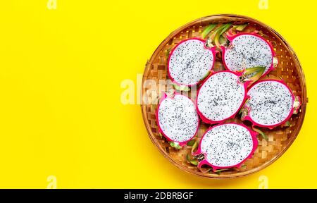 Ripe dragonfruit or pitahaya in wooden bamboo threshing basket on yellow background. Copy space Stock Photo
