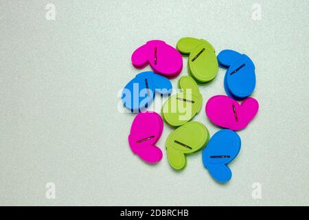 Colourful set of nine plastic clothespins or pegs on a light green sparkling background with copy field. View from above. Stock Photo