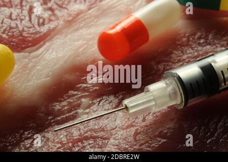 Raw steak with pills and syringe Stock Photo