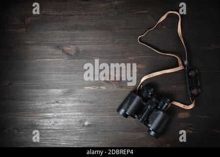 Black military binoculars on wooden background. Lot of copy space for your text. Flat lay. Stock Photo