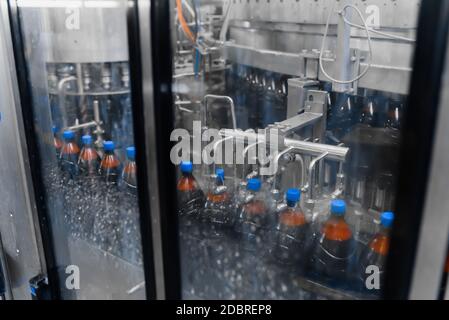 Automatic bottle washer on the beer filling line. Bottle washing process after capping Stock Photo