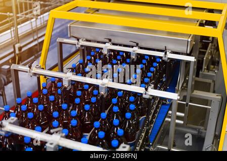 Automatic line for vacuum packaging in a brewery. Plastic brown bottles on conveyor belt Stock Photo