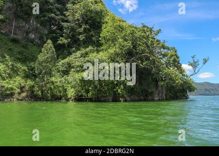 Sailing a traditional fishing boat from the village of Trunyan to a unique cemetery. High mountains covered with dense tropical vegetation line the co Stock Photo