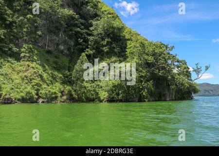 Sailing a traditional fishing boat from the village of Trunyan to a unique cemetery. High mountains covered with dense tropical vegetation line the co Stock Photo