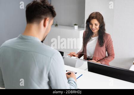 Client Signing Invoice At Hotel Reception Desk Stock Photo