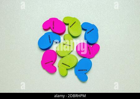 Colourful set of nine plastic clothespins or pegs on a light green sparkling background with copy field. View from above. Stock Photo