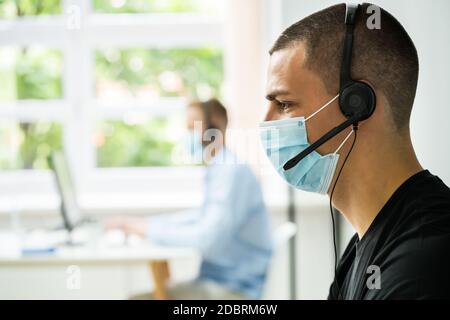 Call Center Telephone Operator In Office Wearing Face Mask Stock Photo