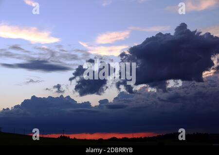 A sunset with dark rain clouds in summer Stock Photo