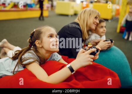 Children plays a game console in the entertainment center. Girl and boy leisures on holidays, childhood happiness, happy kids Stock Photo